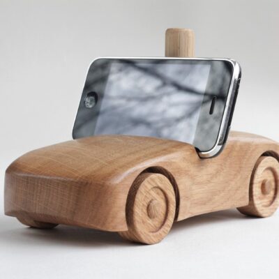 Oak wood phone stand in the shape of a car f- front and side visible, black phone